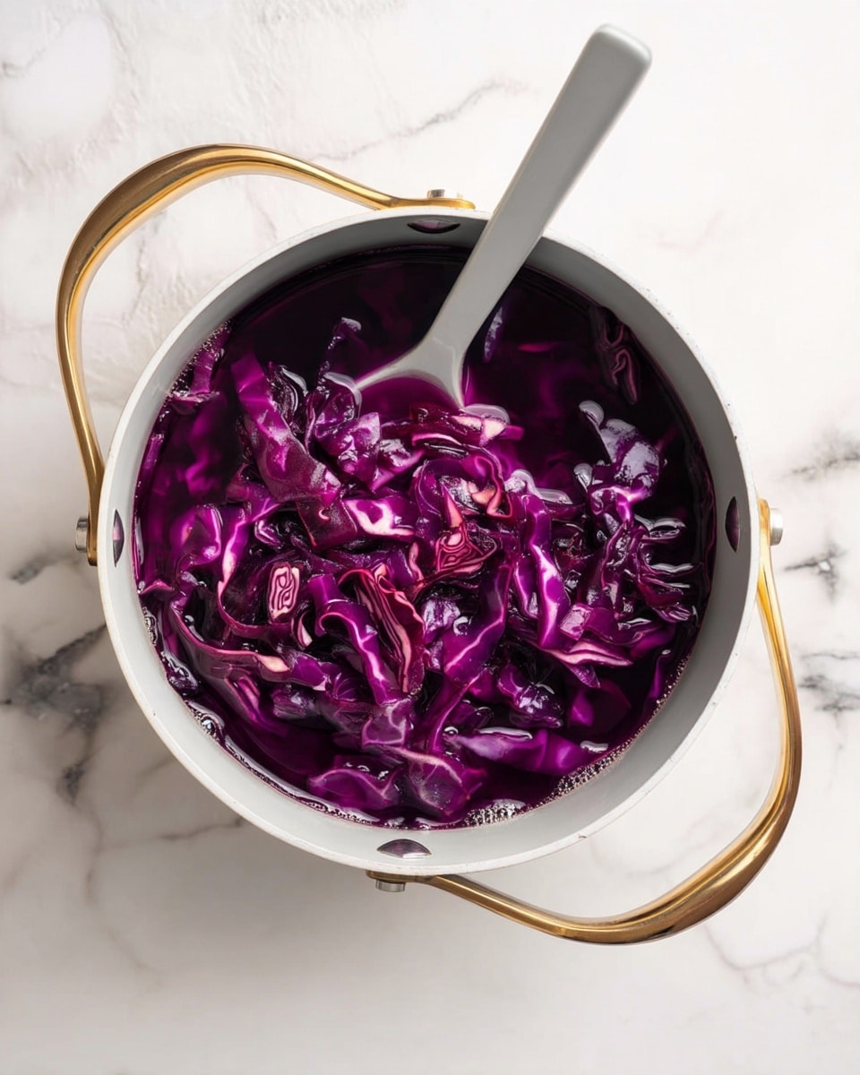 Quick Pickled Cabbage Recipe 4 A white pot with gold handles sits on a white marbled surface, filled with shredded purple cabbage submerged in dark purple liquid. A white spoon rests inside the pot, partially covered by the cabbage. The cabbage layers are thin and uneven, showing white veins running through the deep purple leaves. The overall look is a mix of bright and dark purple with hints of white from the cabbage veins. Photo taken with an iphone --ar 4:5 --v 7