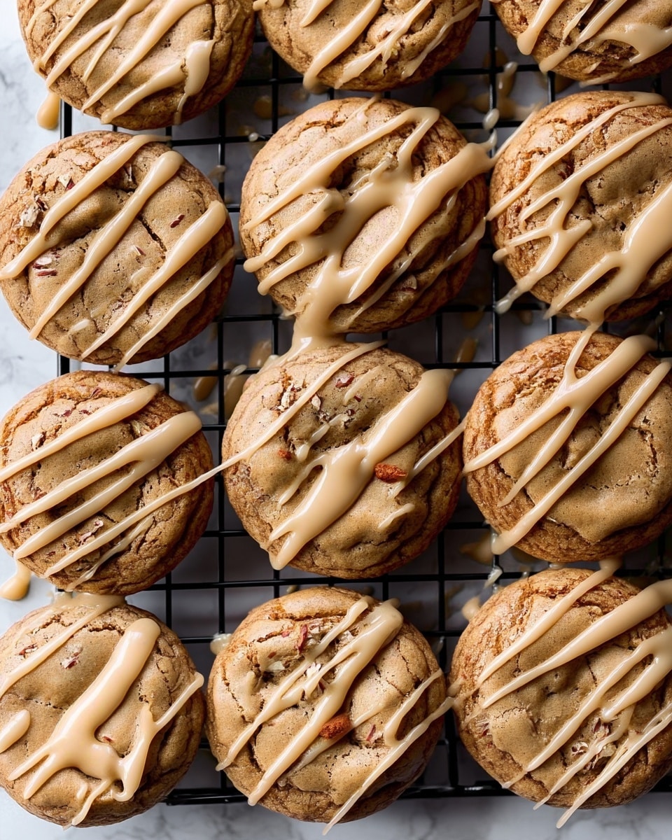 A stack of three thick cookies is shown on a white marbled surface. The bottom cookie is round with a slightly cracked light brown texture. The middle cookie is similar but drizzled with a smooth light tan glaze on top in thin lines. The top cookie is bitten, revealing a soft inside filled with small dark chocolate bits and nuts, and it also has parts covered with the same light tan glaze. The cookies look soft and chunky, stacked one on top of another with some crumbs around. Photo taken with an iphone --ar 4:5 --v 7