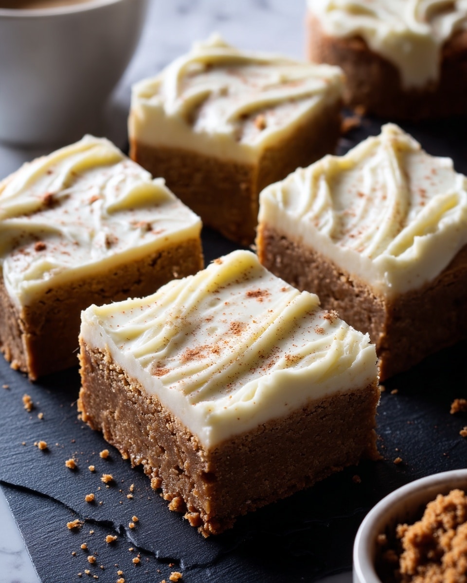 The image shows a white plate with a grid of light brown bars topped with a thick, creamy white frosting sprinkled with light brown spices. The bars are cut into squares with smooth, even layers, the bottom layer having a firm, crumbly texture, and the top layer being soft and creamy with swirled patterns. One square is lifted slightly off the plate, showing its thickness and the clean edge between the two layers. The plate is placed on a white marbled surface with soft natural light casting gentle shadows. photo taken with an iphone --ar 4:5 --v 7