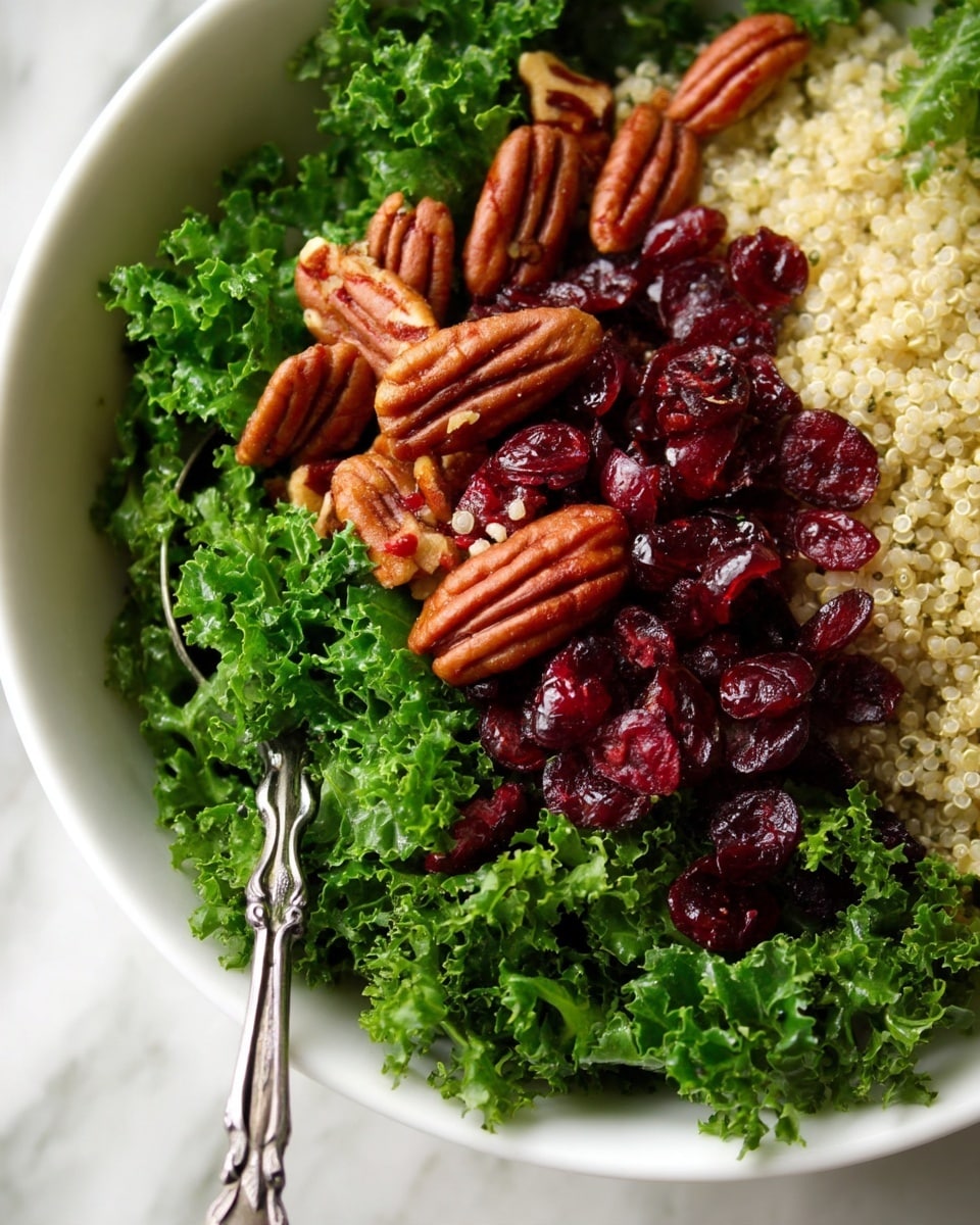 Cranberry Kale Quinoa Salad with Candied Pecans and Feta Recipe 5 A wooden bowl filled with a salad made of three main layers: the bottom layer is light beige quinoa with tiny red quinoa mixed in, the middle layer is bright green chopped kale leaves, and the top layer has dark red dried cranberries scattered throughout with small pieces of chopped brown nuts adding texture. A detailed silver spoon rests diagonally in the bowl. The bowl is placed on a white marbled surface with scattered kale leaves and bowls of nuts and quinoa nearby. photo taken with an iphone --ar 4:5 --v 7